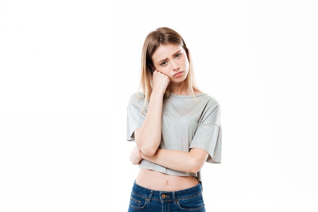 Sad young woman standing isolated over white wall