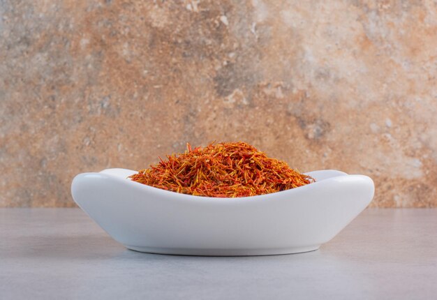 Saffron seeds in a white plate on concrete background. 