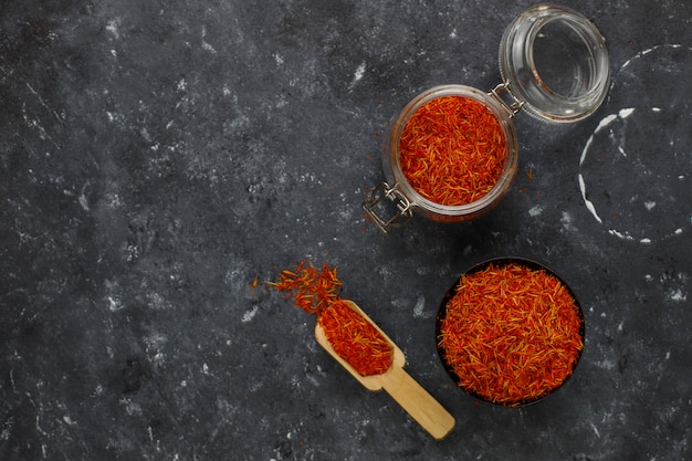 Saffron spice herb in wooden spoon, black background