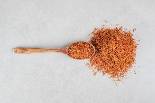 Saffron spices in a wooden spoon on concrete.