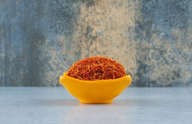 Saffron spices in a yellow ceramic cup on blue background. High quality photo