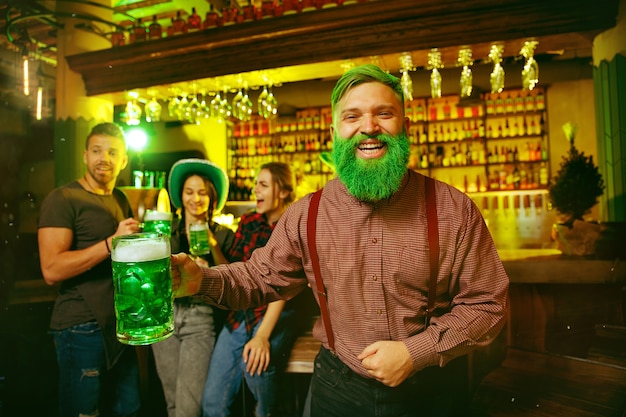 Free photo saint patrick's day party. happy friends are celebrating and drinking green beer.