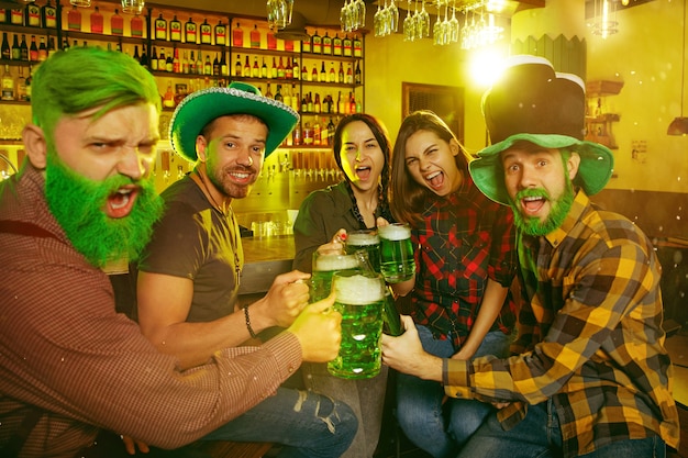 Festa di san patrizio. gli amici felici stanno festeggiando e bevendo birra verde.