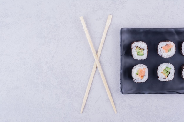 Sake maki rolls with salmon and avocado in a black ceramic platter.