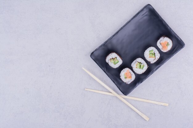 Sake maki rolls with salmon and avocado in black platter.