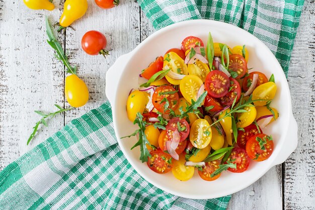 Salad of fresh cherry tomatoes with onion and arugula