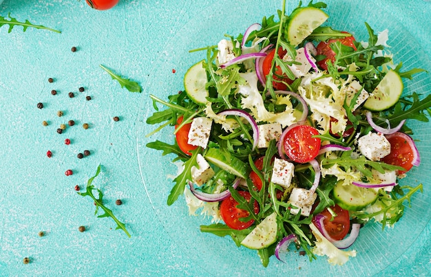 Salad of fresh vegetables - tomato, cucumber and feta cheese in Greek style. Flat lay. Top view