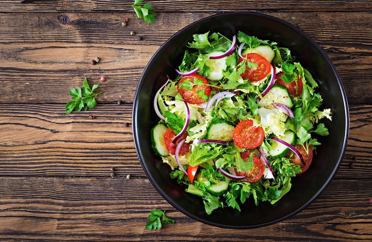 Free Photo salad from tomatoes, cucumber, red onions and lettuce leaves. healthy summer vitamin menu. vegan vegetable food. vegetarian dinner table. top view. flat lay