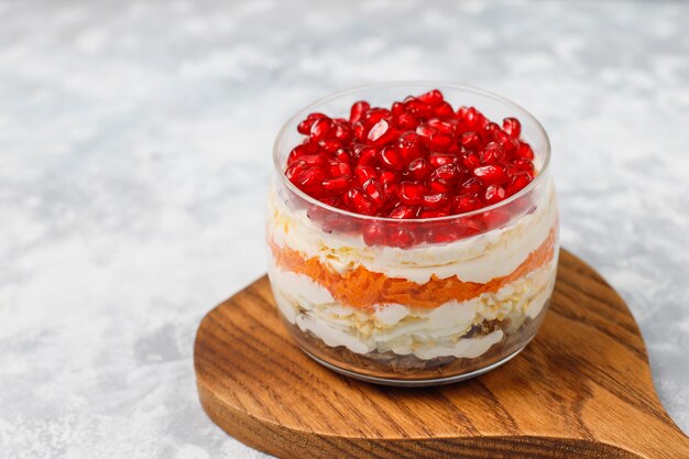 Salad Garnet bracelet. Vegetable salad with pomegranate seeds with pomegranate on concrete 