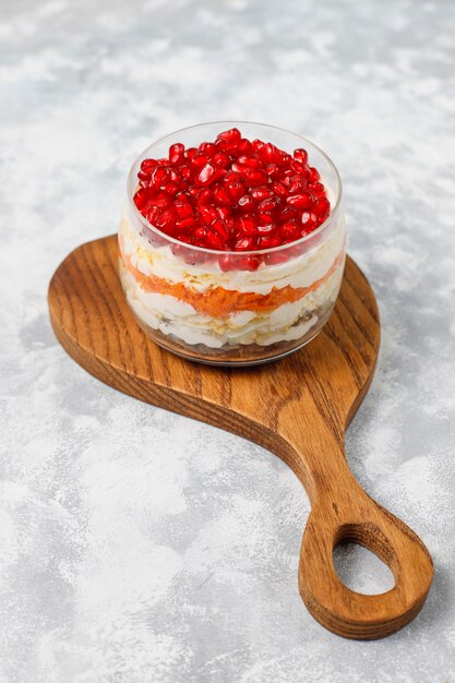 Salad Garnet bracelet. Vegetable salad with pomegranate seeds with pomegranate on concrete 