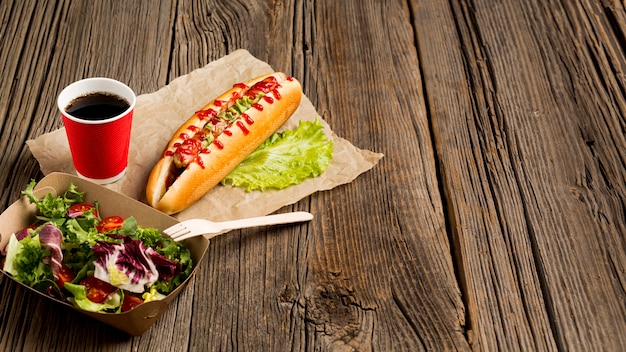 Salad and hot dogs on wooden background