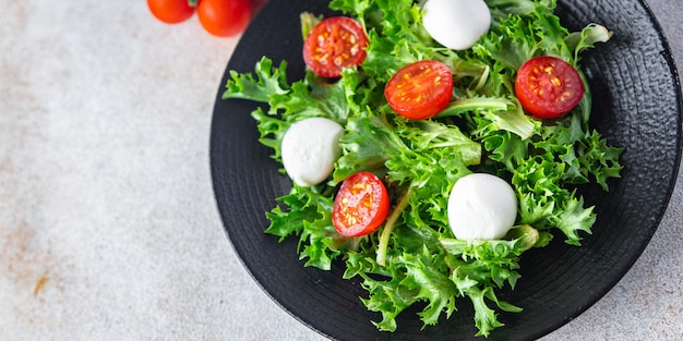 Salad mozzarella tomato lettuce arugula healthy meal food diet snack on the table copy space