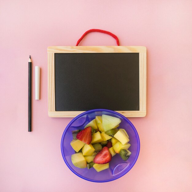 Salad near pencil and chalkboard