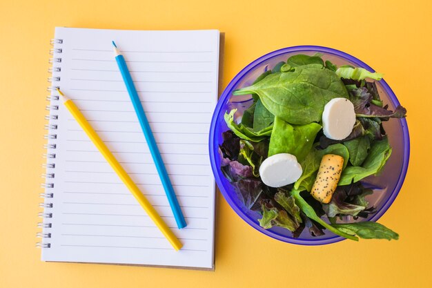 Salad near pencils and notebook