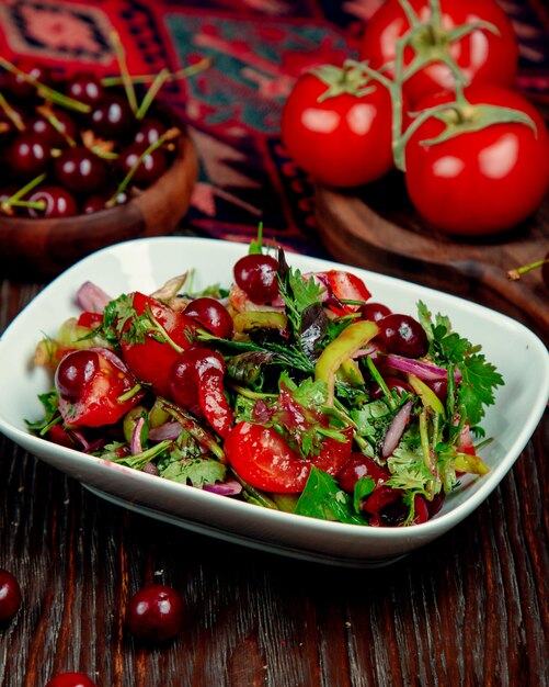 Salad of tomatoes herbs onions and cherries in soy sauce