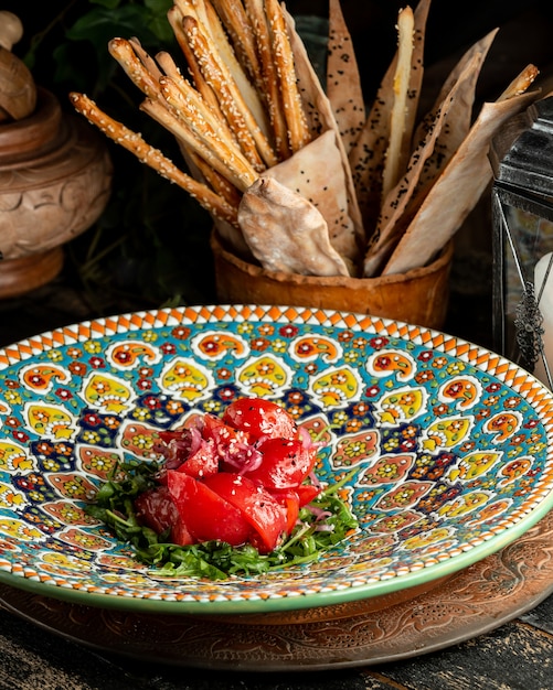 Бесплатное фото Салат с рукколой томатным красным луковым маслом и кунжутом в тарелке с хлебом