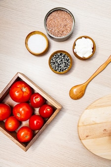 Салат с сельдереем, помидорами и тунцом. ингредиенты салата в процессе приготовления на деревянном столе