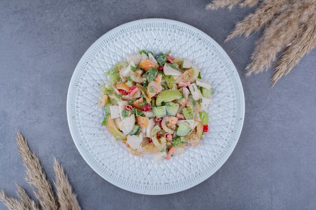 Salad with chopped herbs and vegetables on concrete surface