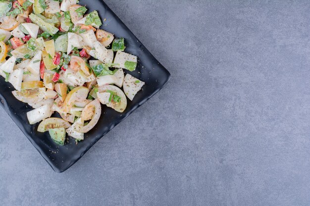 Salad with chopped herbs and vegetables on concrete surface