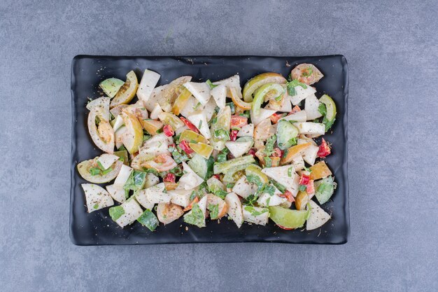 Salad with chopped vegetables and herbs on blue surface