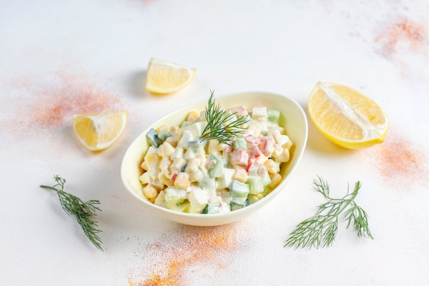 Insalata con bastoncini di granchio, uova, mais e cetriolo.