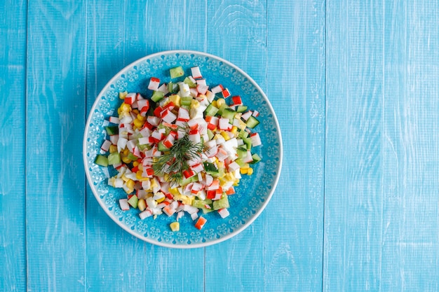 Salad with crab sticks, eggs, corn and cucumber.