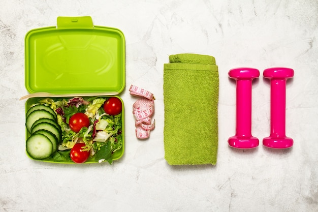 Salad with dumbbells and a green towel