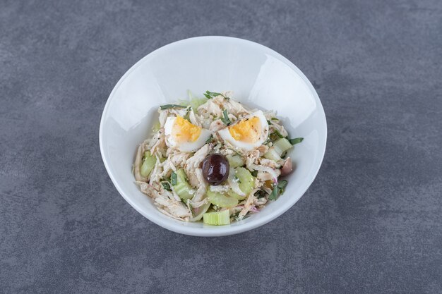 Salad with eggs and diced chicken in white bowl.