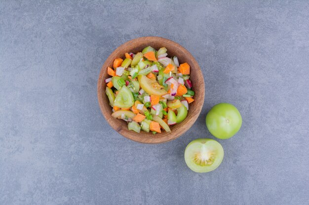 木製の皿に緑の野菜とチェリートマトのサラダ