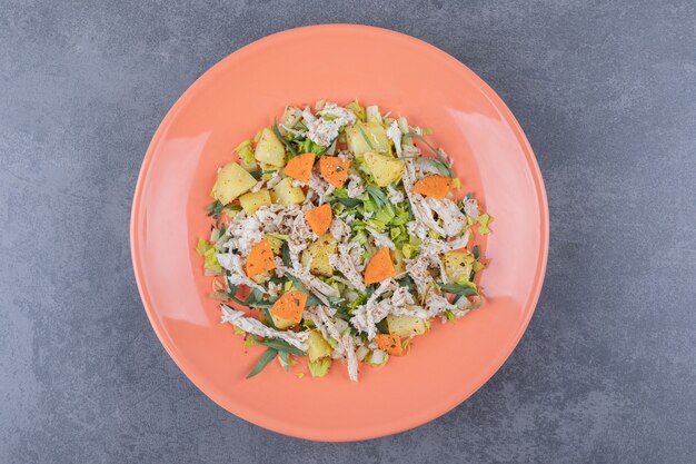 Salad with minced chicken on orange plate.