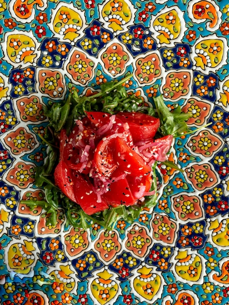 salad with tomato red onionrugula oil and sesame on plate