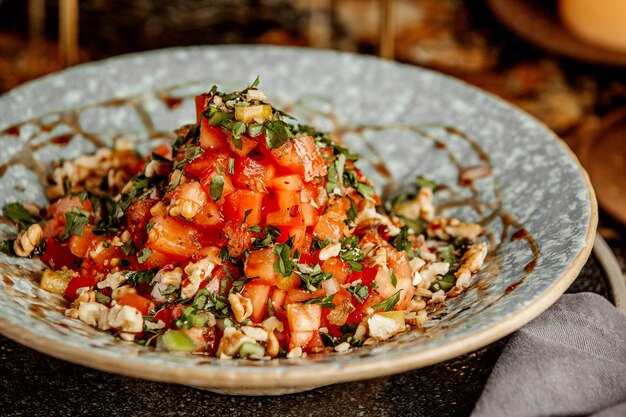 Salad with tomatoes nuts and herbs in a deep plate