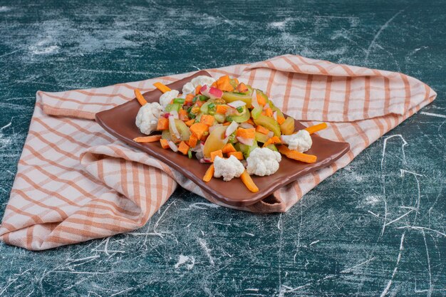 Salad on a wooden platter with chopped ingredients and herbs. 