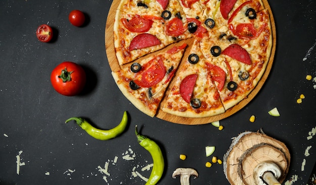 Foto gratuita pizza salame condita con pomodoro fresco e fette di olive vista dall'alto
