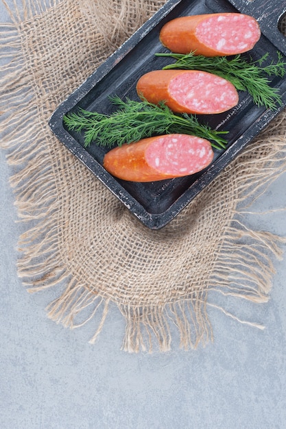 Бесплатное фото Колбаса салями с кусочками на черной тарелке.