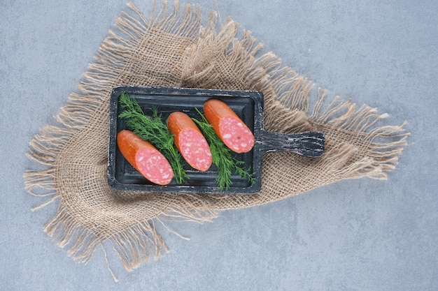 Foto gratuita fette di salame sul tagliere nero.