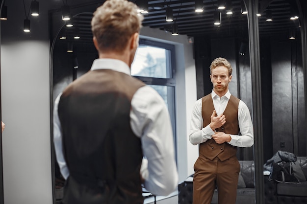 Free photo sale, shopping, fashion, style and people concept. elegant young man choosing clothes in mall or clothing store.