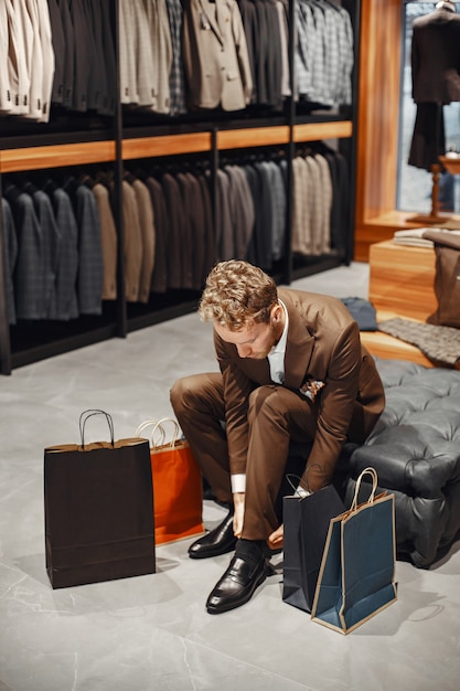 Free photo sale, shopping, fashion, style and people concept. elegant young man choosing footwear in mall.