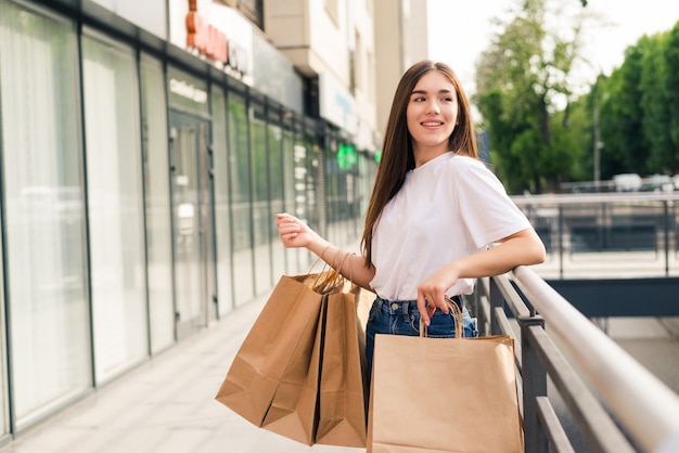 Продажа, шоппинг, туризм и концепция счастливых людей - красивая женщина с хозяйственными сумками в городе