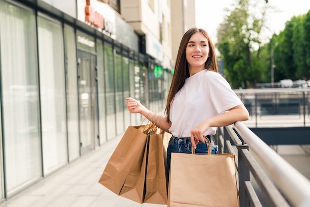 販売、ショッピング、観光、幸せな人々のコンセプト-街の買い物袋を持つ美しい女性