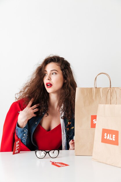 Sale woman sitting with paper shopping bags and looking away