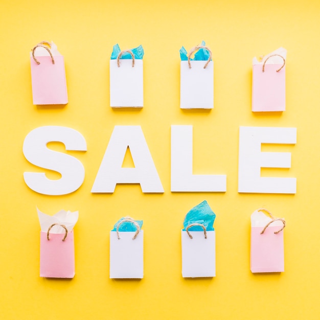 Free photo sale word with row of filled shopping bags on yellow background