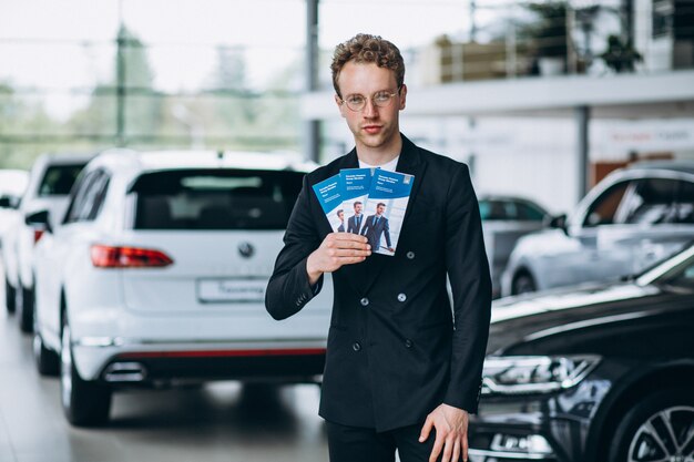 Salesman at a car showroom with business flyers