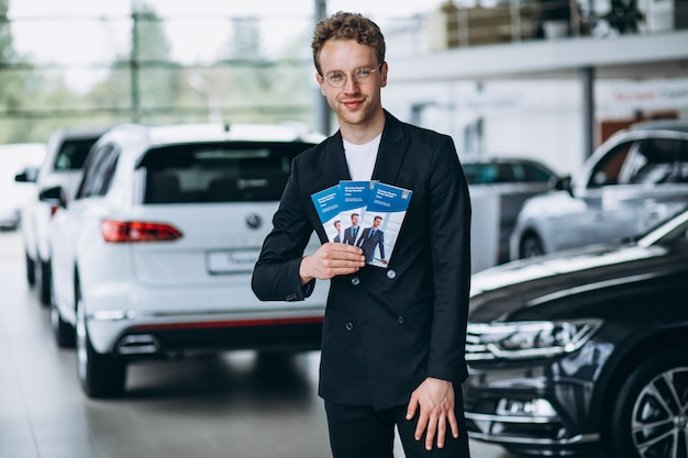 Salesman at a car showroom with business flyers