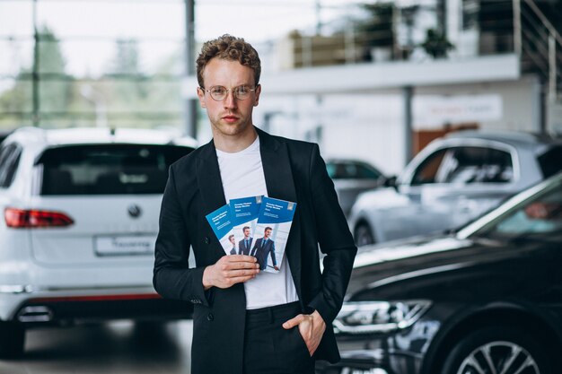 Salesman at a car showroom with business flyers