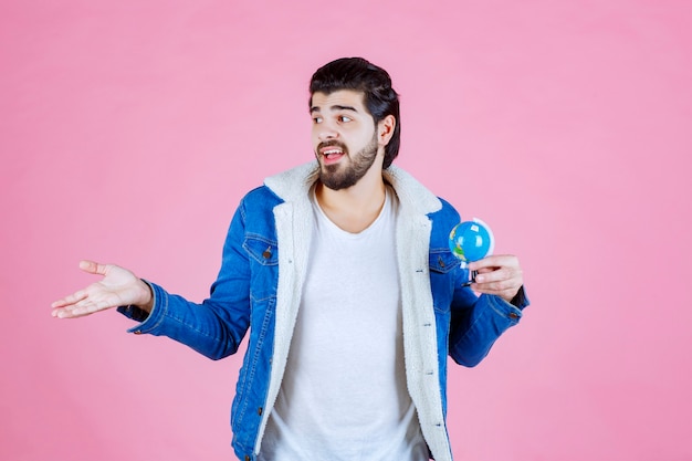 Free photo salesman holding a mini globe and promoting the product