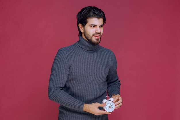 A salesman holding a white alarm clock and promoting it to the customer. 