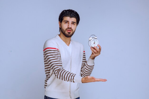 salesman holding a white alarm clock to sell.