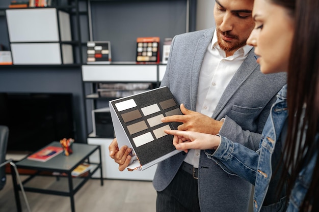 Free photo salesman shows color swatches to lady customer for new kitchen furniture