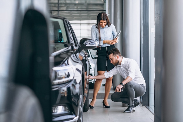 Salesman and woman looking for a car in a car showroom